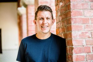 Paul standing by brick wall